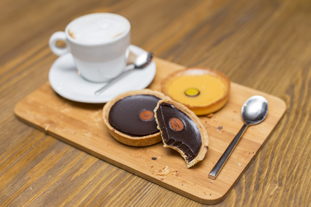 Dark chocolate and lemon tarts with cappuccino on the tableの写真素材