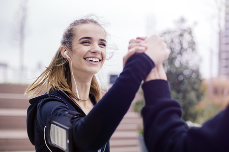 Young woman is shaking the arm of her personal trainer after successful trainingの写真素材