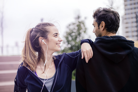 Male coach helping young woman exercising at outdoors in urban environmentの写真素材