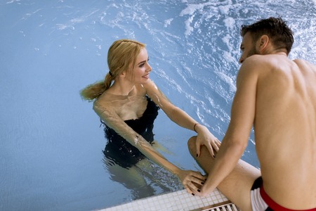 Loving couple relaxing in the spa center by the swimming pool