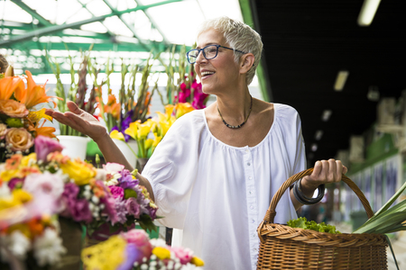 Charrming senior woman buying  flowers on local marketの写真素材