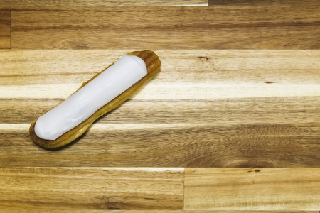 Eclair crispy creamy cake with white chocolate isolated on wooden background