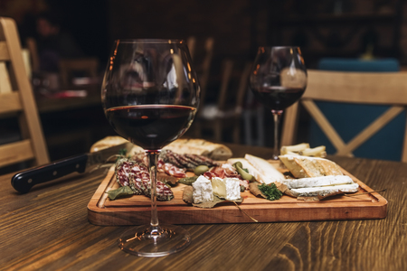 Cheese, sausages and red wine as an appetizer served at wooden tableの写真素材