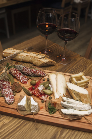 Cheese, sausages and red wine as an appetizer served at wooden tableの写真素材