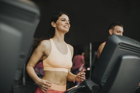 Young couple running on treadmills in modern gym