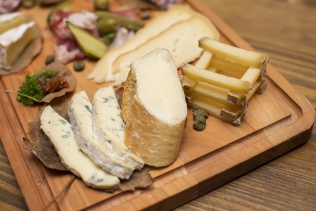 Cheese and sausages as an appetizer served at wooden tableの写真素材