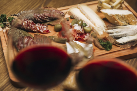 Cheese, sausages and red wine as an appetizer served at wooden tableの写真素材