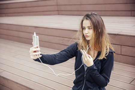 Portrait of young sporty woman taking selfie outdoorの写真素材