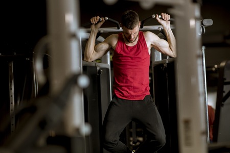 Athletic man doing workouts for a back with power exercise machine in a gym club