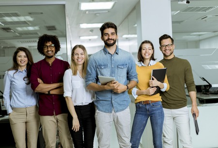 Portrait of young successful creative business team looking at camera and smiling in the office