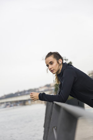 Smiling young woman with smartphone and headphones listening to music outdoorの写真素材