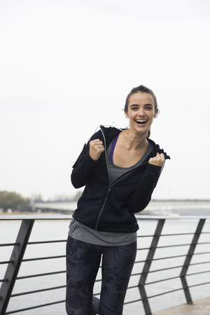 Smiling young woman with smartphone and headphones listening to music outdoorの写真素材