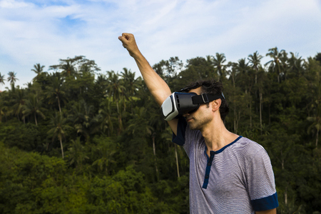 Young man wearing VR glasses in the tropicalforestの写真素材