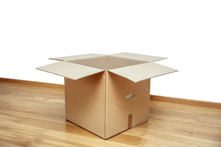 Open cardboard box on the floor in empty room, ready for transport
