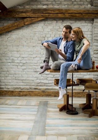 Beautiful young couple is using a digital tablet and smiling in kitchen at homeの写真素材