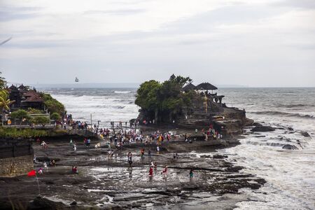 BALI, INDONESIA - JANUARY 26, 2019: Unidentified people by Tanah Lot temple at Bali, Indonesia. It...