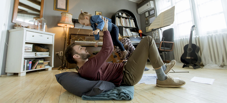 Happy young family with cute girl playing on the floor at rustic roomの写真素材