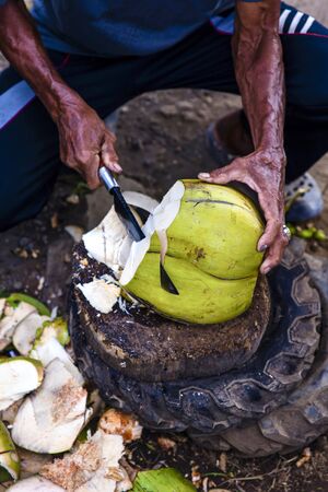 Closeup of a man chopping coconut with big knife