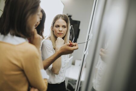 Group of young business women discussing in front of glass wall using post it notes and stickers at startup officeの写真素材