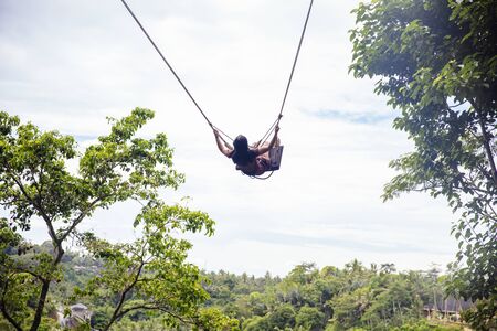 Young tourist woman swinging over the tropical rainforest at Bali island, Indonesia