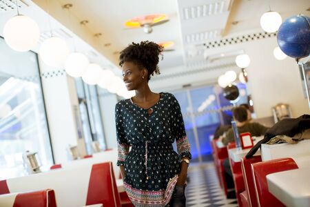Pretty young african american woman standing by the bar in the diner