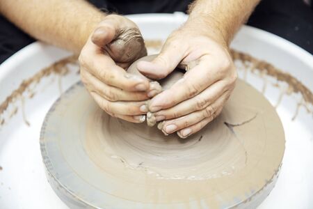 Close up detail view at an artist makes clay pottery on a spin wheel