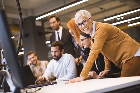 Senior businesswoman working together with young business people in modern officeの写真素材