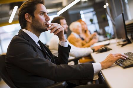 View of businessman executive in group meeting with other businessmen and businesswomen in modern...