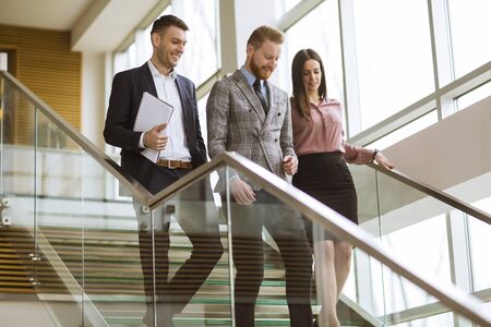 Young business partners analyze the business results while walking down the stairs in modern office