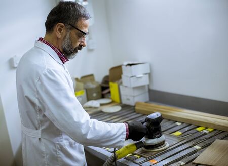 View at handsome senior engineer in the laboratory examines ceramic tiles