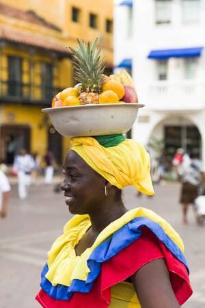 CARTAGENA, COLOMBIA - SEPTEMBER 16, 2019: Unidentified palenquera, fruit seller lady on the street of Cartagena, Colombia. These Afro-Colombian women come from village San Basilio de Palenque, just outside the city.のeditorial素材