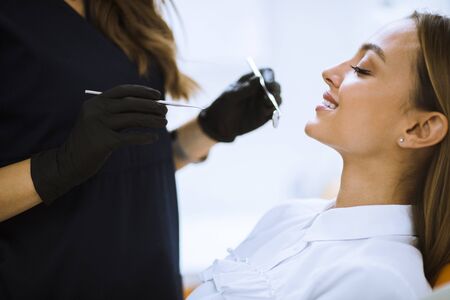 Close-up of female with open mouth during oral checkup at the dentist office