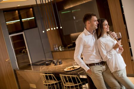 Sweet young couple drinking red wine after romantic dinner at luxury kitchenの写真素材