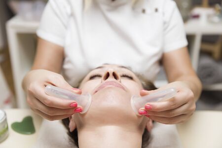 Closeup of cup applied to facial skin of a female patient as part of the traditional method of...