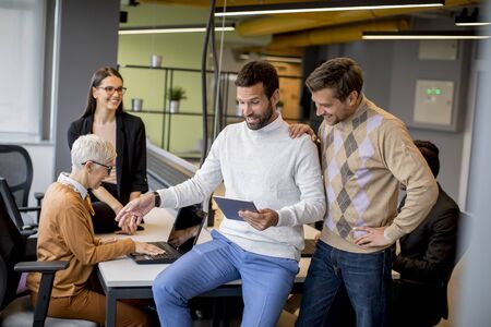 Group of business people working and communicating while standing in  the office together with...