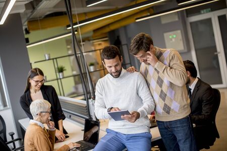 Group of business people working and communicating while standing in  the office together with...