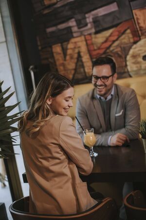 Lovely young couple sitting in the cafe and drinking orange juiceの写真素材