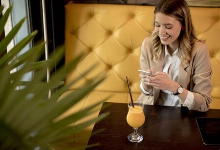 Charming yung woman using mobile phone in the cafeの写真素材