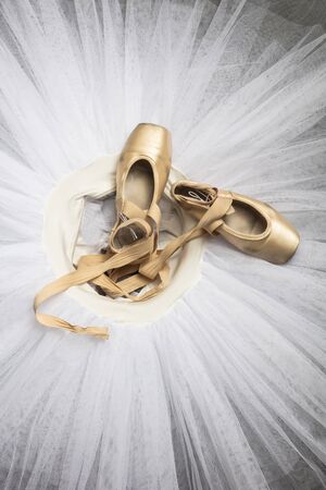 Professional ballet shoes with ribbons on a white tutu in a dance studio