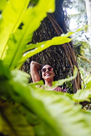 A female tourist is sitting on a large bird nest on a tree at Bali island, Indonesiaの写真素材
