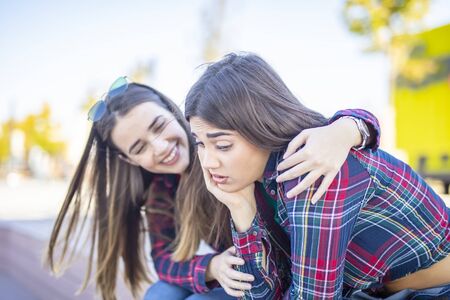 Young woman comforts a sad female friend in the park
