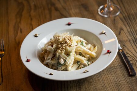 Penne with chicken, spinach and hazelnut in parmesan sauce on the tableの写真素材