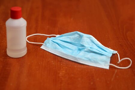 Closeup ofaAlcohol bottle and surgical mask as concept of deep cleaning of surfaces for virus desease preventionの写真素材