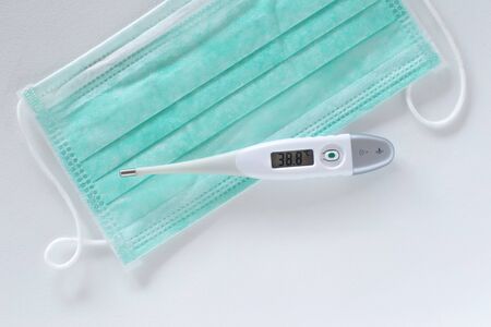 Surgical ear-loop mask and thermometer on the table