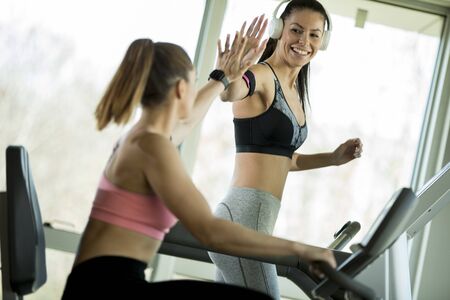 Pretty young woman using treadmill in modern gym