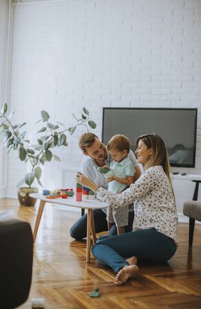 Cute little boy playing with toys in the living room with father and motherの写真素材