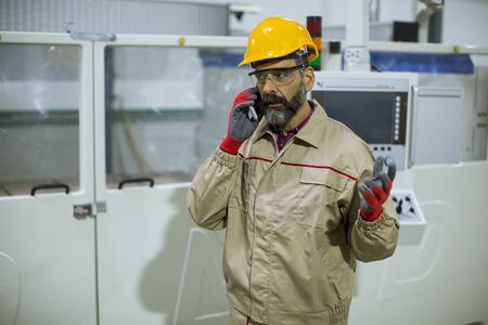 Portrait of mature industrial man engineer with smartphone in a factory