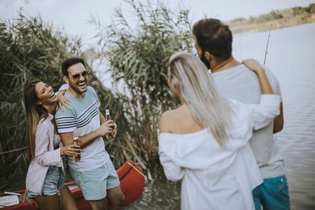 Group of happy young friends enjoying the nature on the lakeside