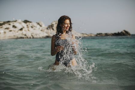 Pretty young woman walking in the warm sea water at summer