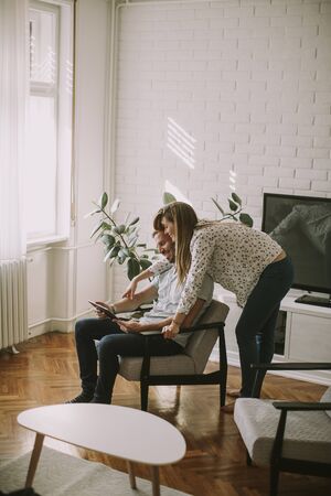 Happy young couple looking at digital tablet in the living roomの写真素材